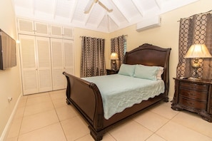 A bedroom with a bed, a nightstand, a lamp, a wardrobe, and a ceiling fan.