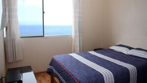 A bedroom with a bed, a window with curtains, and a desk. - Departamento, 3 dormitorios, vista al Mar (San Miguel)