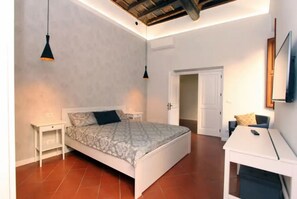 A bedroom with a bed, bedside tables, a desk, and a chair. There is a door leading to another room. - A Modern and Large 3 Bedrooms Apartment near Piazza Navona (Roma)