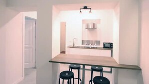 Una cucina compatta con isola centrale, sgabelli da bar e forno a microonde.
