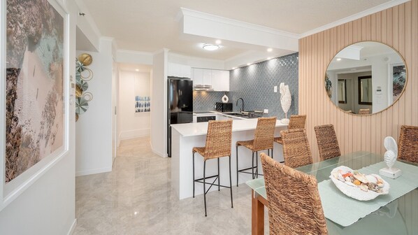 Una cocina moderna con armarios blancos, un refrigerador negro y un salpicadero de azulejos.