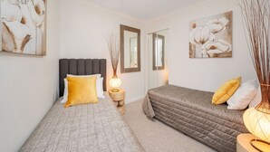A bedroom with a bed, bedside table, lamp, and two wall-mounted mirrors.