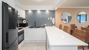 A modern kitchen with a central island, white cabinetry, and a backsplash with a geometric pattern.
