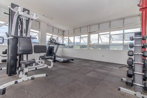 A gym with cardio equipment, weight benches, and a treadmill.