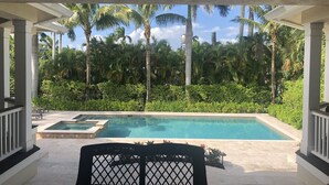 A covered outdoor area with a pool, surrounded by palm trees and lush greenery. - 8M Dollar Home, 3 Houses from Beach in Old Naples! (Naples)