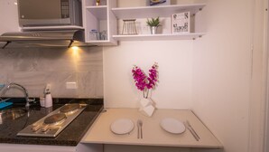 A modern kitchen with a built-in microwave, a sink with a faucet, and a dining area with two white plates and cutlery. - Modern Loft in Chapinero Alto (Bogotá)