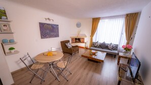 A living room with a sofa, coffee table, and a fireplace. There is a dining table with chairs and a TV on a stand. - Modern Loft in Chapinero Alto (Bogotá)
