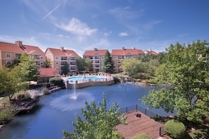 A residential building complex with a swimming pool, a fountain, and a wooden deck.