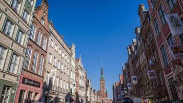 A bustling street with historic buildings, a prominent clock tower, and various shops.