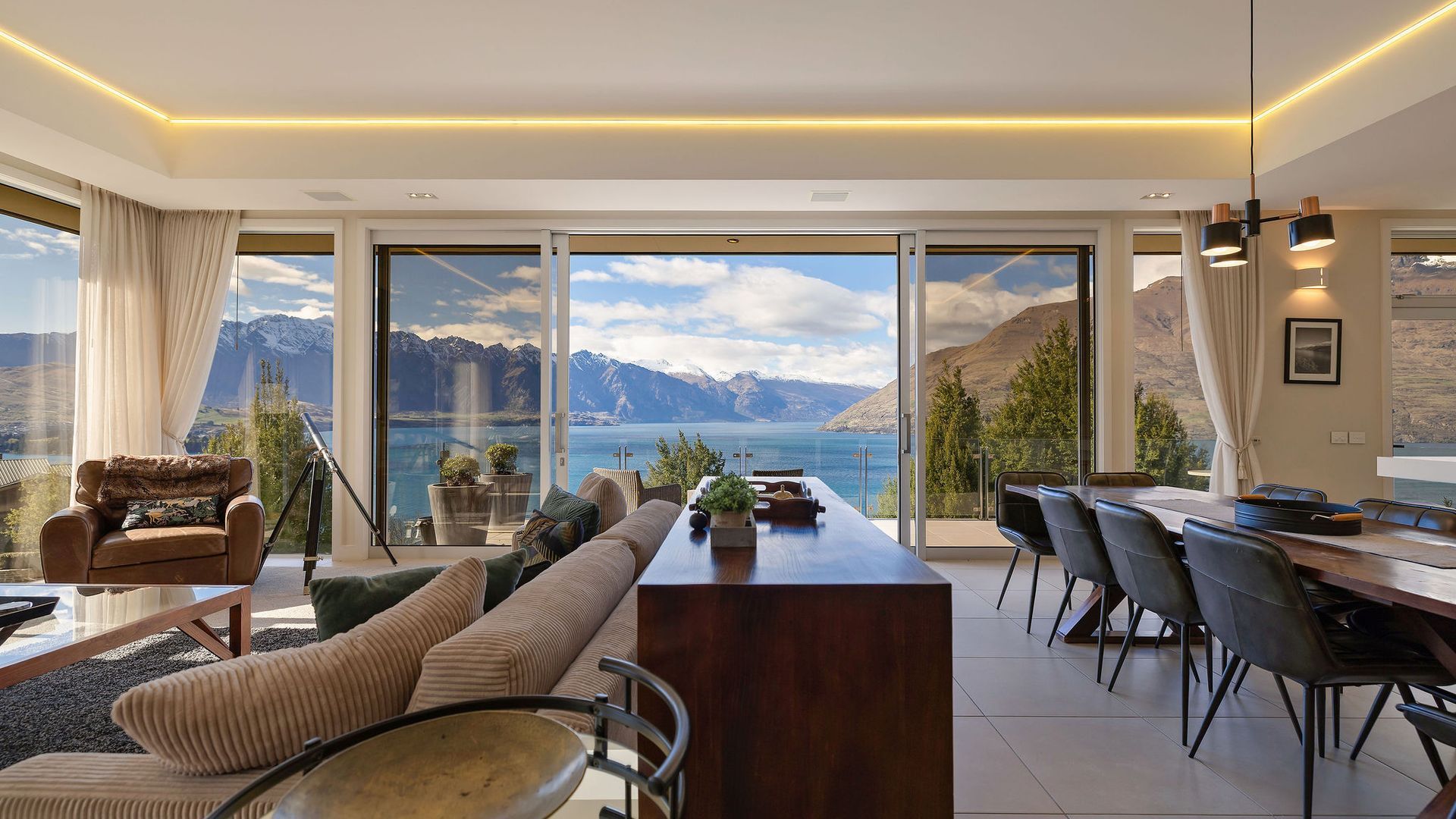 Un interior moderno con un amplio ventanal panorámico, una zona de comedor y un sofá.