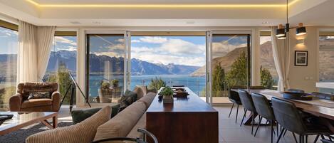 Un interior moderno con un amplio ventanal panorámico, una zona de comedor y un sofá.