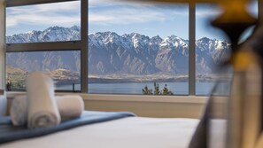 A hotel room with a large window offering a view of snow-capped mountains and a lake. - Q by the Lake Aspen Grove Stunning Views (Queenstown)