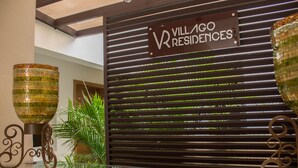 Letrero de Villagio Residences con diseño moderno, una mesa de vidrio con adornos y una planta en maceta.