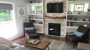Ein Wohnzimmer mit Kamin, Wandfernseher und Bücherregal.