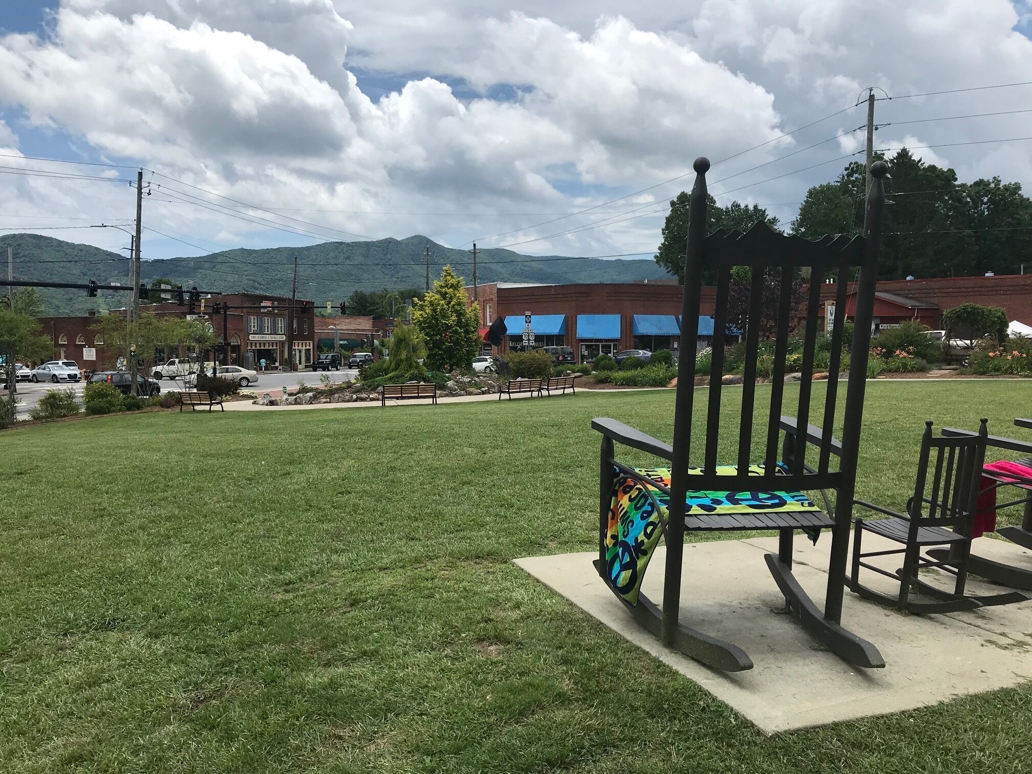 A grassy area with a playground, benches, and a picnic table.