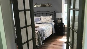 Ein Schlafzimmer mit einem Bett, einem Nachttisch und einem Wandschild mit der Aufschrift 'Soulmates'.