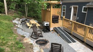 Eine Terrassenfläche mit Feuerschale, Gartenmöbeln und einer Holzterrasse.