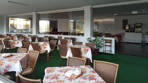 A restaurant with outdoor seating, wicker chairs, and tables covered with floral tablecloths. - International Resort (Chácara Roma)