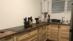 A kitchen with wooden cabinets, a black countertop, and a stainless steel sink. - Beautiful Apartment at Miramar (Santurce)