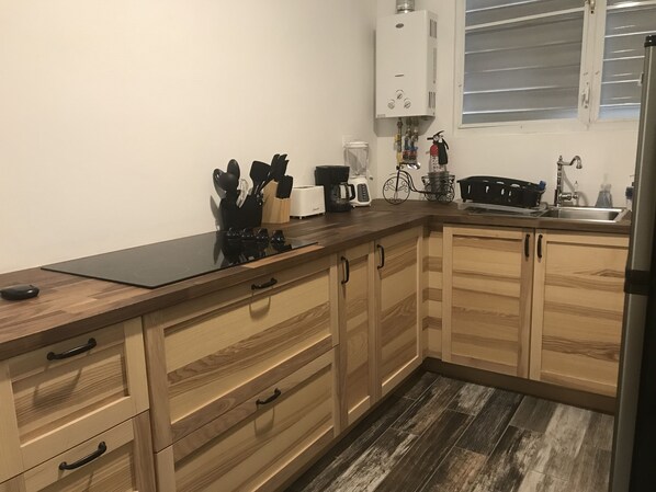 A kitchen with wooden cabinets, a black countertop, and a stainless steel sink.