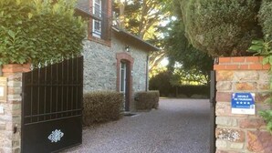 Un bâtiment en pierre avec une allée en gravier et un portail noir.