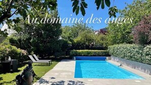 Une piscine à l’eau d’un bleu limpide, entourée d’un jardin bien entretenu et ornée d’une statue.