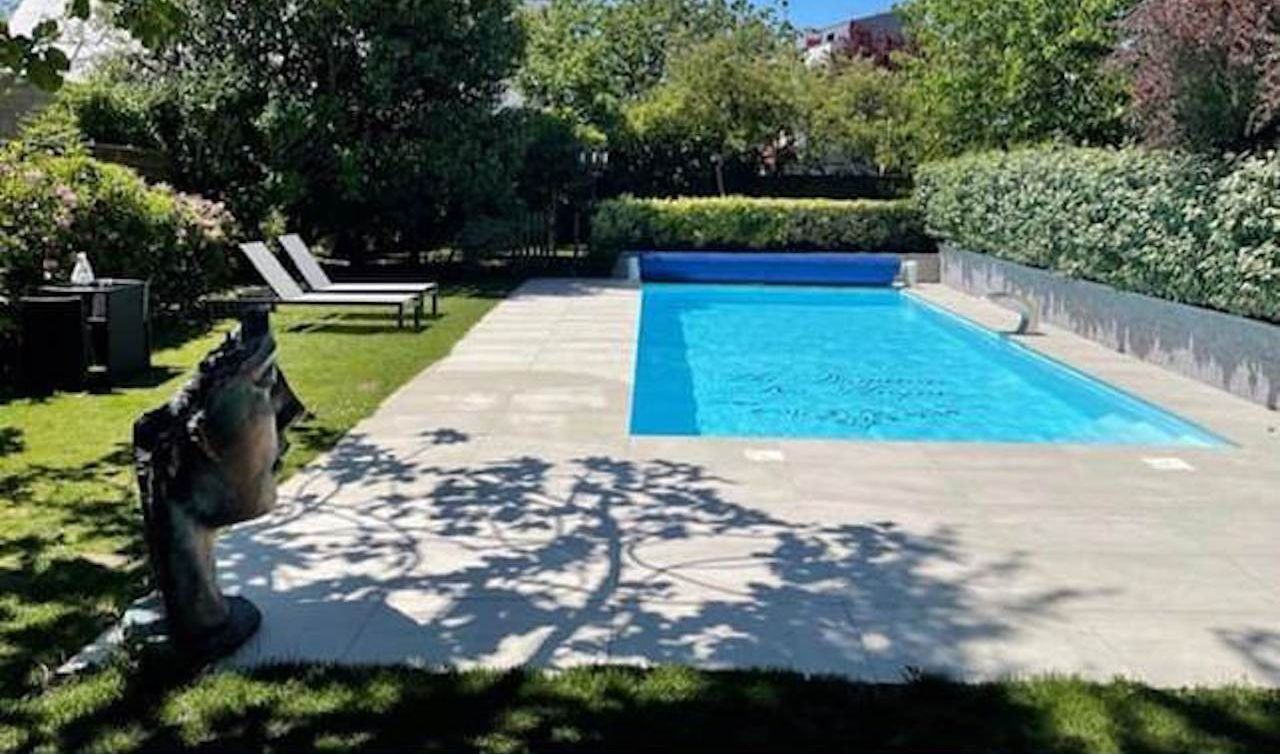 Une piscine à l’eau d’un bleu limpide, entourée d’un jardin bien entretenu et ornée d’une statue.