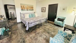 A bedroom with a bed, a chair, a desk, and a door.
