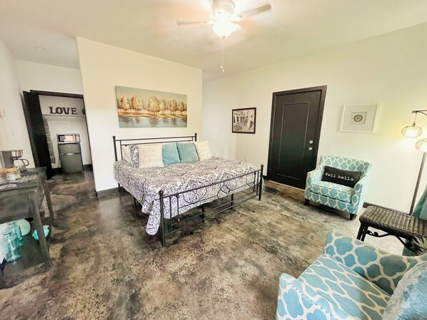 A bedroom with a bed, a chair, a desk, and a door.