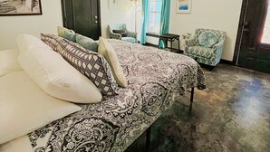 A bedroom with a bed, a chair, a television, and a ceiling fan.