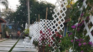 Un chemin de jardin bordé d’une clôture en treillis blanc, une statue d’enfant et des plantes en fleurs.