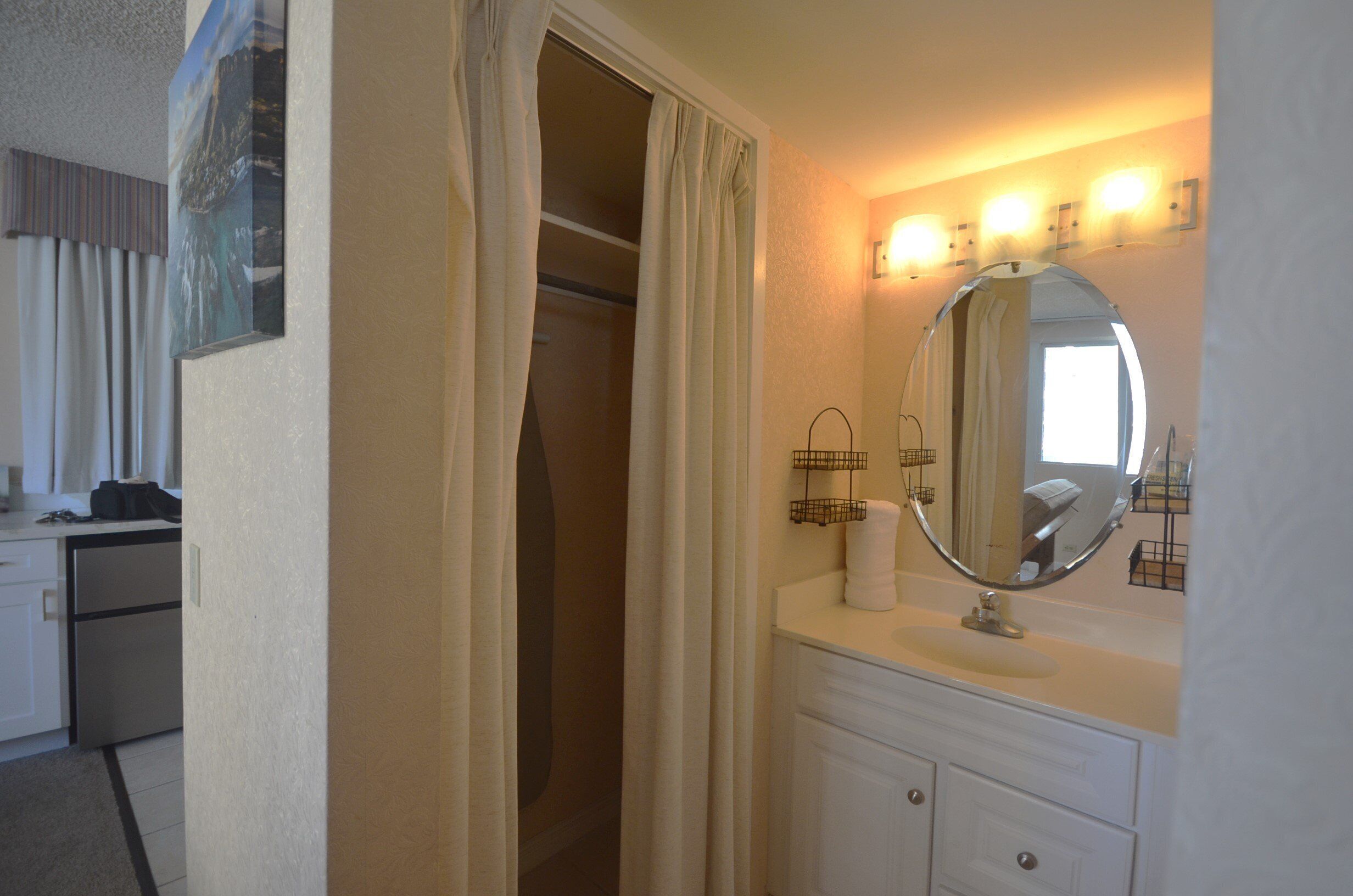 A bathroom with a vanity, mirror, and lights.