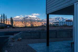 A modern building with a concrete patio, a view of a snow-capped mountain, and a clear sky.