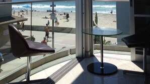 Ein Zimmer mit großem Fenster und Meerblick, einem Glastisch und einem Stuhl.