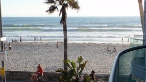 Eine Terrasse direkt am Strand mit Sitzgelegenheiten im Freien, einem Grill und Blick auf Strand und Meer.