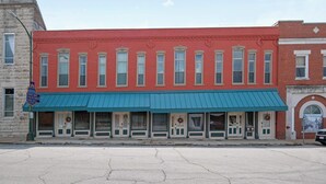 A red building with a blue awning and multiple doors, likely a commercial establishment. - Crossroads Flat:  Steps away from Rt. 66 & Carthage square (Carthage)