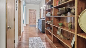 A hallway with a patterned ceiling, wooden shelves with decorative items, and a patterned rug. - Crossroads Flat:  Steps away from Rt. 66 & Carthage square (Carthage)