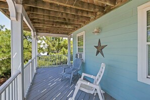 A covered porch with two white chairs, a star decoration on the wall, and a wooden ceiling. - Koinania Cottage | 245 ft from the Beach | Private Pool (Virginia Beach)