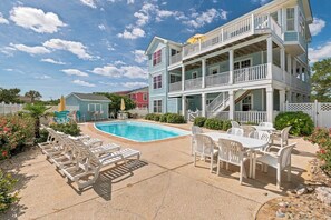 A two-story building with a pool, outdoor seating, and a fenced area.