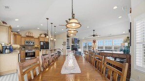 Une cuisine spacieuse dotée de meubles en bois, d’un îlot central et de luminaires suspendus.