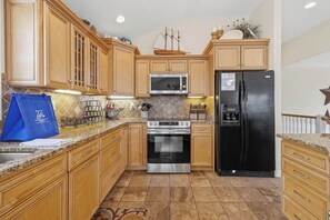 A kitchen with wooden cabinets, a stainless steel oven, a black refrigerator, and a microwave. - Koinania Cottage | 245 ft from the Beach | Private Pool (Virginia Beach)