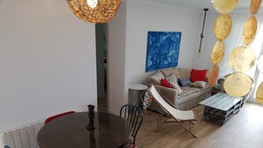 A dining area with a round table and chairs, a sofa, and a hanging light fixture. - Deltamar 80 Solo Familias! (Xeraco Playa)