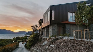 A modern two-story house with a stone facade, large windows, and a view of the sea and mountains. - Lakehouse Joela | Award winning luxury home | Close to central Queenstown (Queenstown)