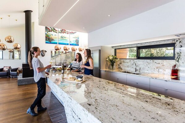 A modern kitchen with a marble countertop, a large window, and a decorative painting on the wall.