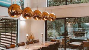 A modern dining area with a large table, multiple chairs, and a hanging spherical light fixture. - Lakehouse Joela | Award winning luxury home | Close to central Queenstown (Queenstown)