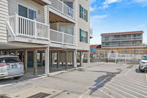 A multi-story building with balconies, a covered parking area, and a visible address sign.