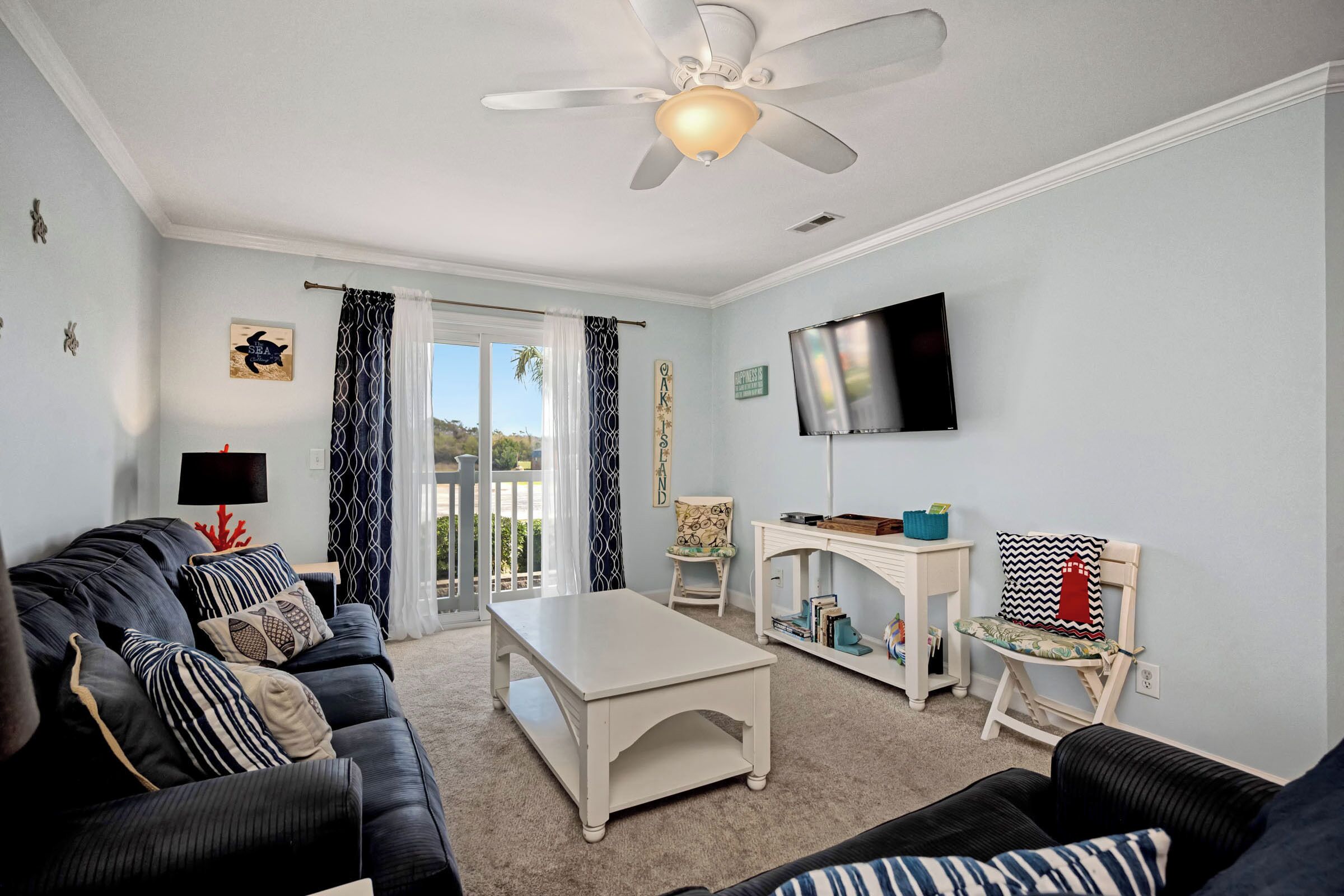 A living room with a sofa, coffee table, TV, and a ceiling fan.