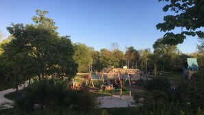 Un parque infantil con diversas estructuras de juego, rodeado de árboles y follaje.