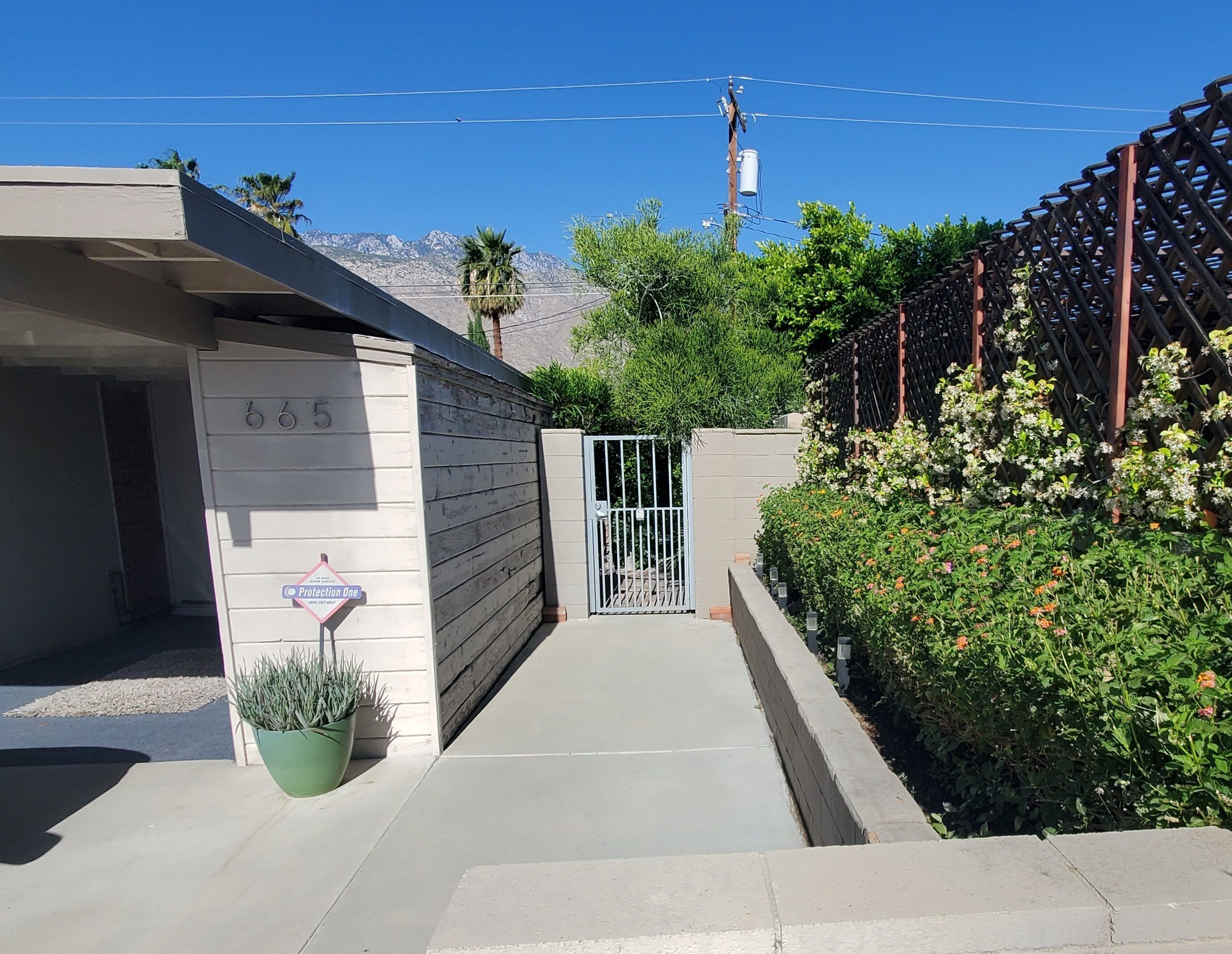 A gated residential area with a concrete pathway leading to a building marked with the number 665.