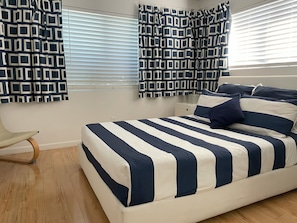 Une chambre à coucher avec un lit, des rideaux, une table de chevet et une chaise.